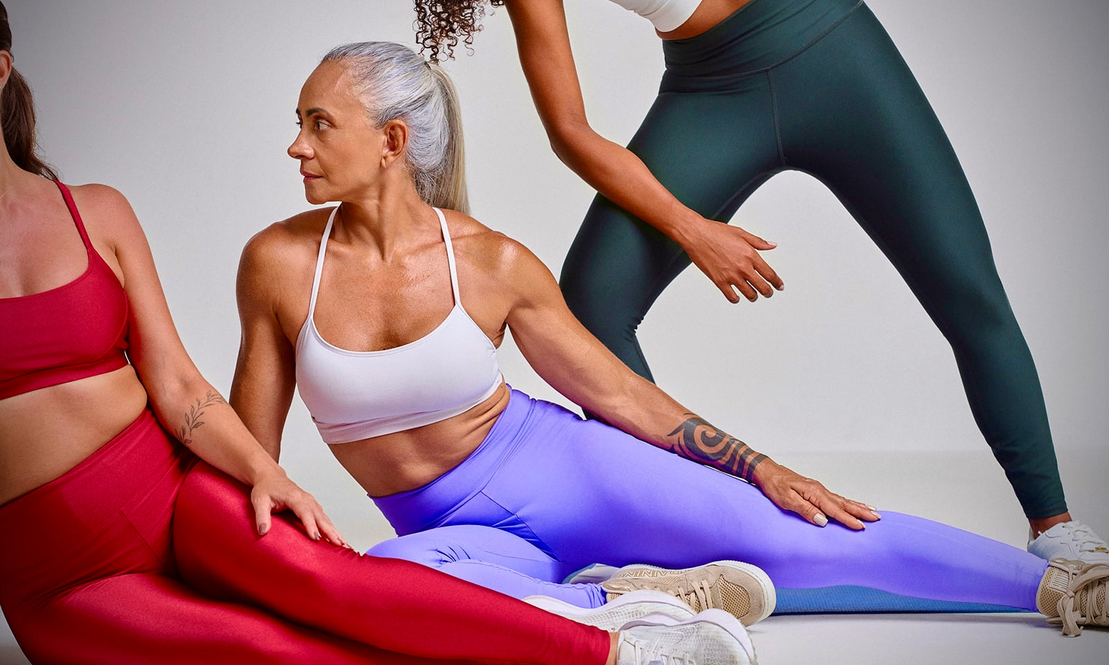 Group of women in activewear sitting together, representing empowered aging, confidence, and strength at every stage of midlife.