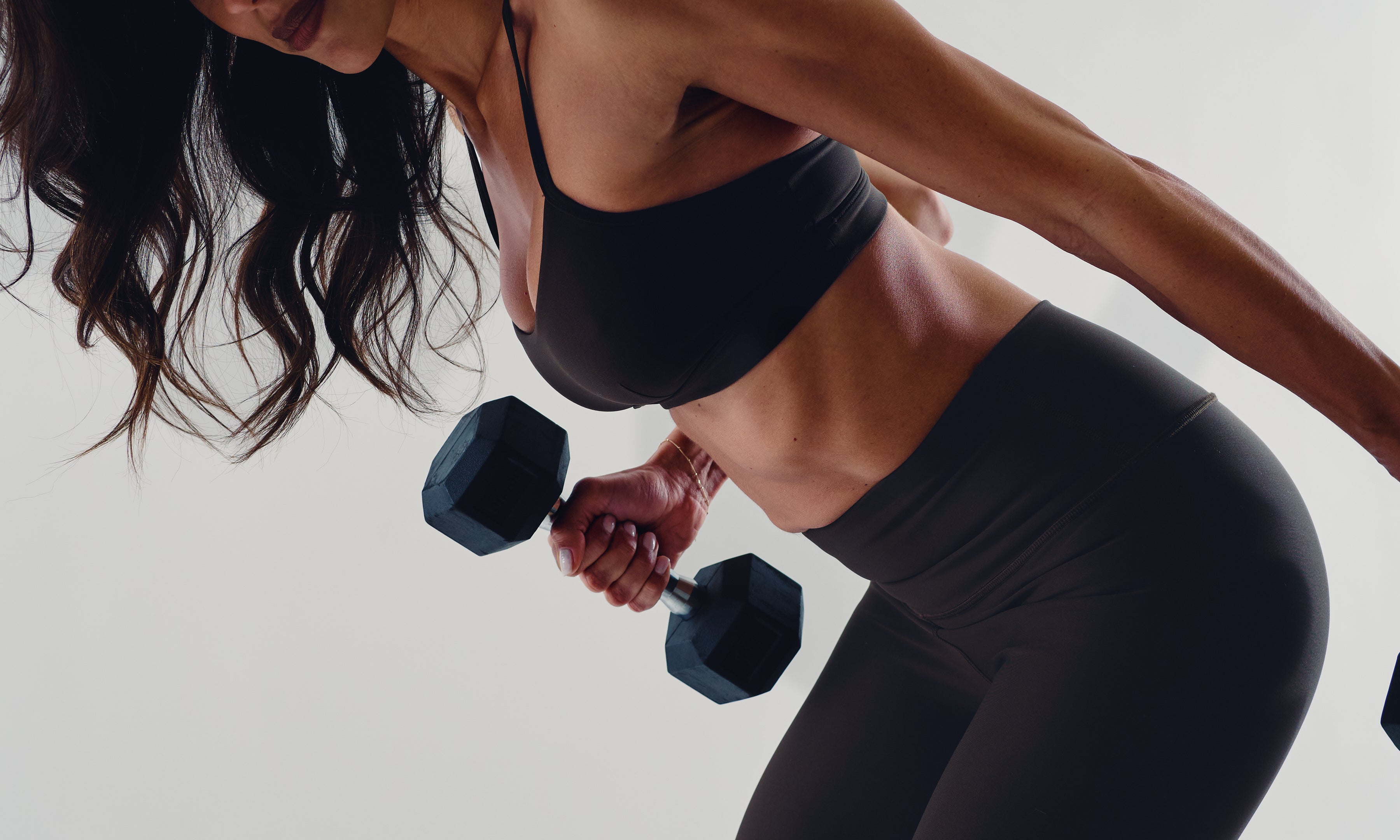 Woman strength training with dumbbells, emphasizing muscle maintenance and functional strength in midlife