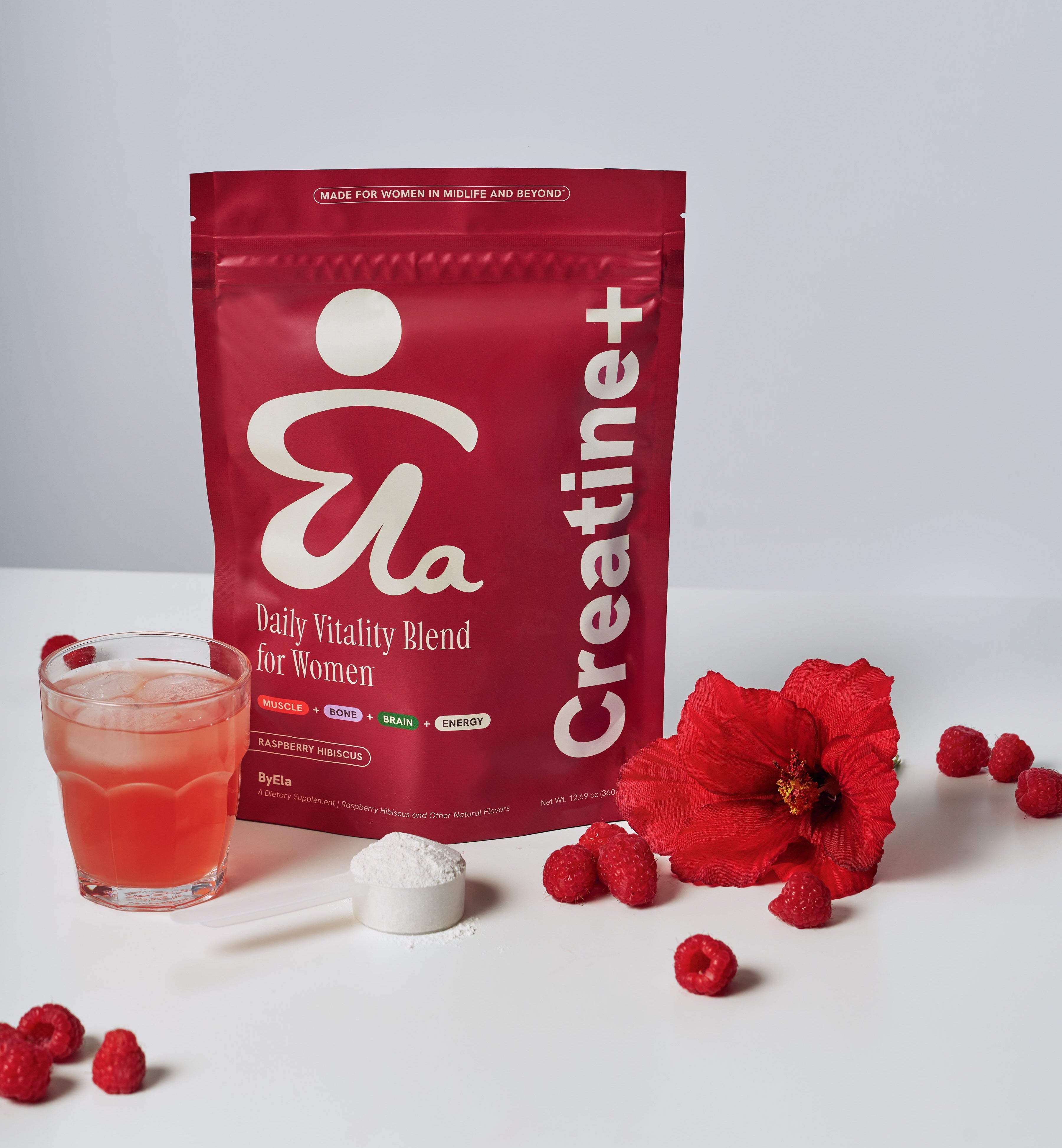 ByEla supplement package labeled 'Creatine+' with a glass of red liquid, raspberries, and a flower on a white background.