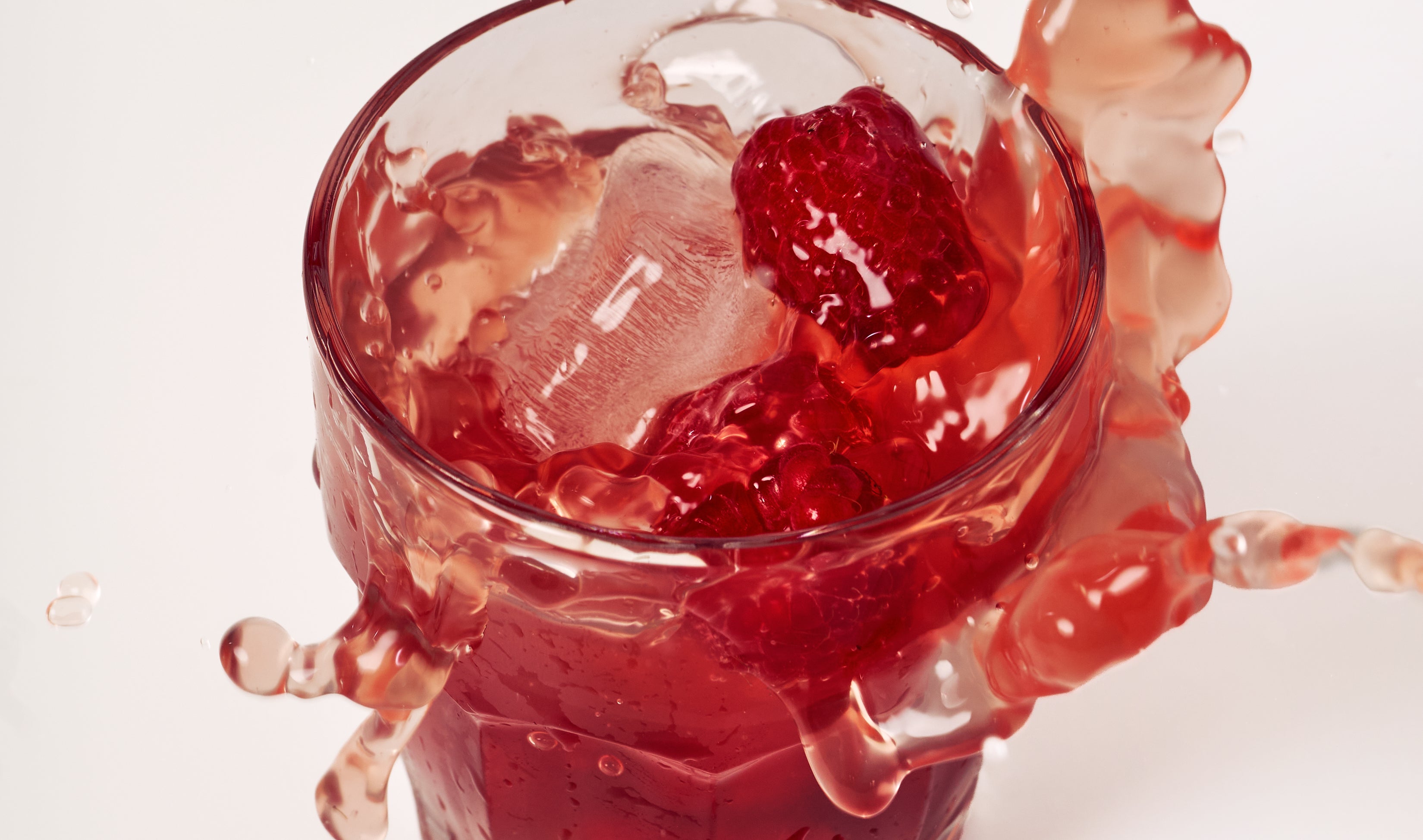 Raspberry hibiscus Creatine+ drink with ice and fresh raspberries, highlighting flavor and refreshment.