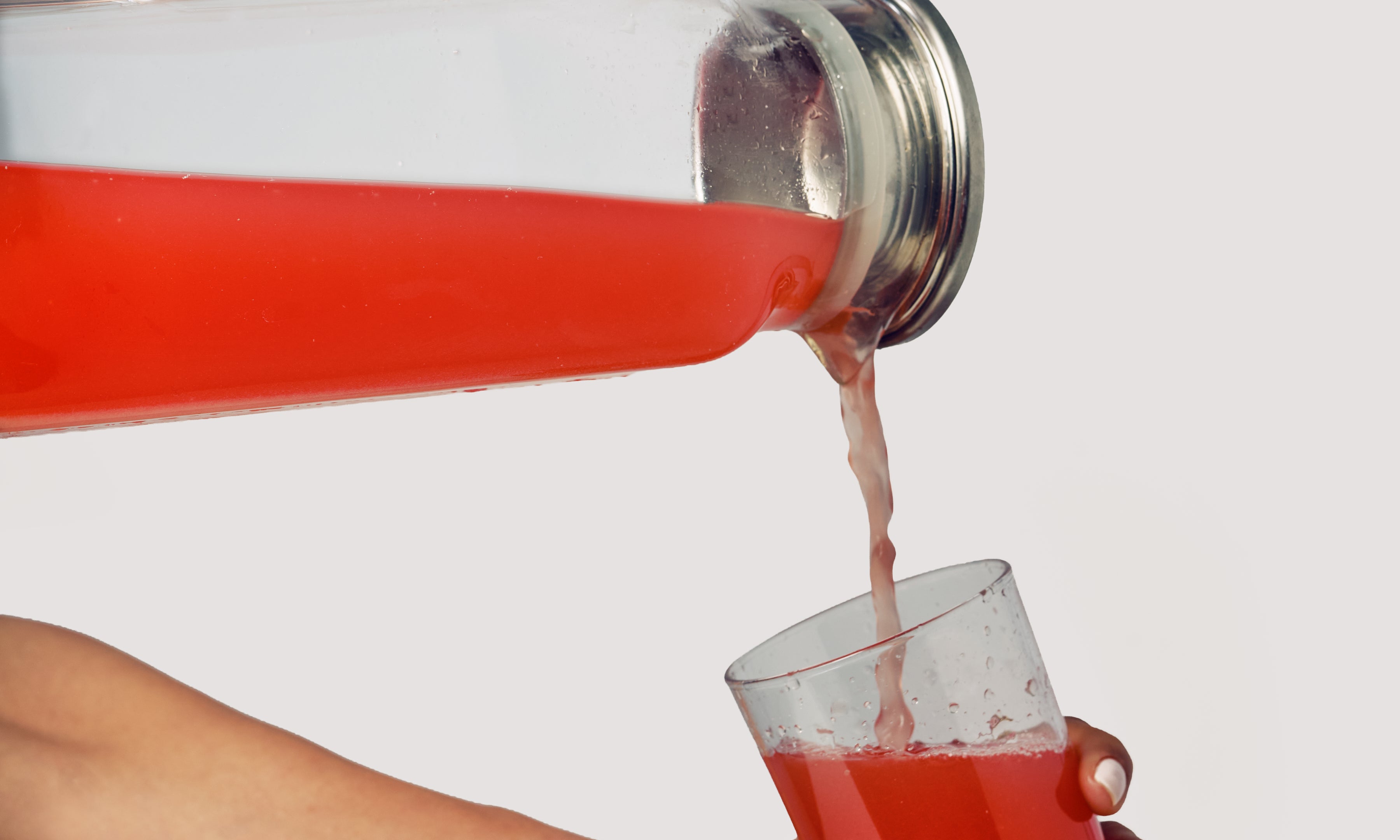 ByEla Creatine+ drink being poured into a glass, showing preparation of a daily strength and vitality supplement.