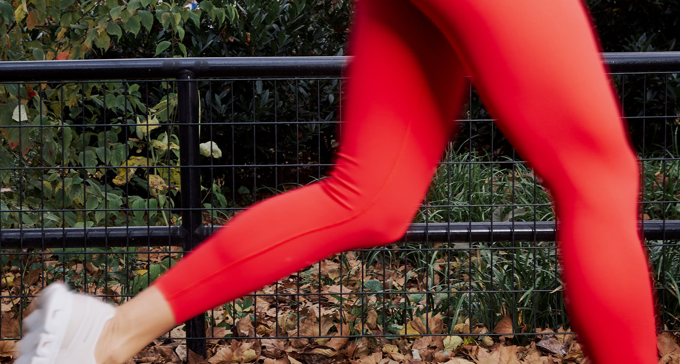 Woman running outdoors in red leggings, representing active lifestyle and muscle health
