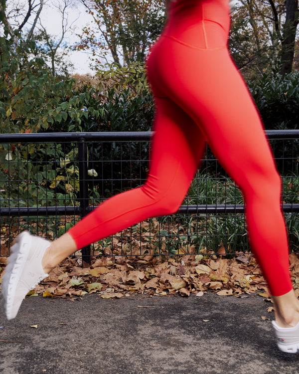 Woman running outdoors in red leggings, representing active lifestyle and muscle health